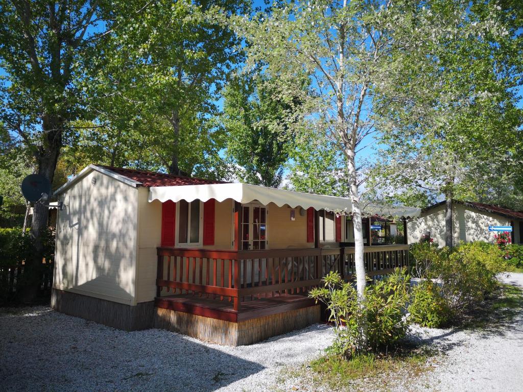een klein huis met een veranda en een hek bij Chalet in Toskana Viareggio Italie nabij Zee, Strand, Airconditioning, Zwembad, Wifi in Viareggio