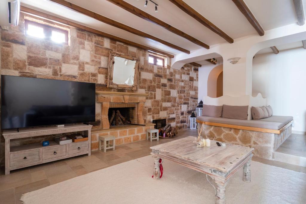 a living room with a large television and a fireplace at Flash House in Spetses