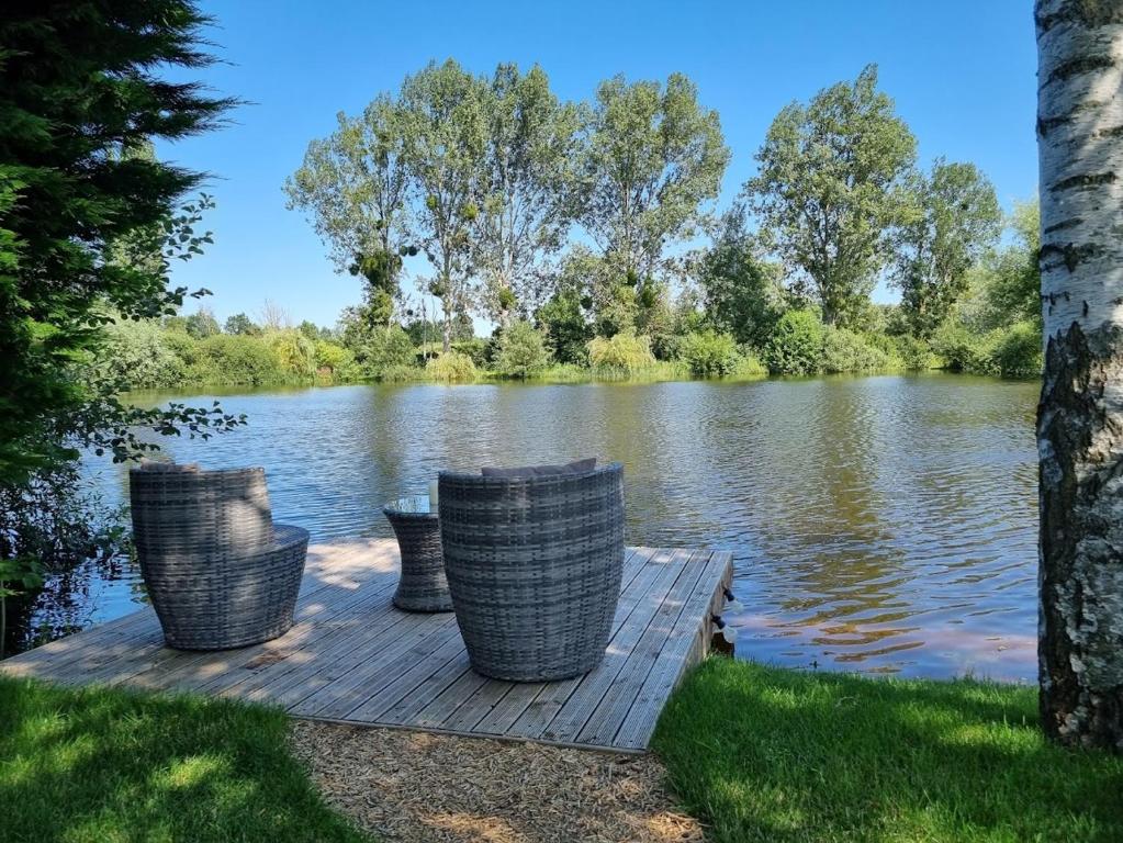 3 chaises assises sur un quai à côté d'un lac dans l'établissement Chalet La Romance, à Prouilly