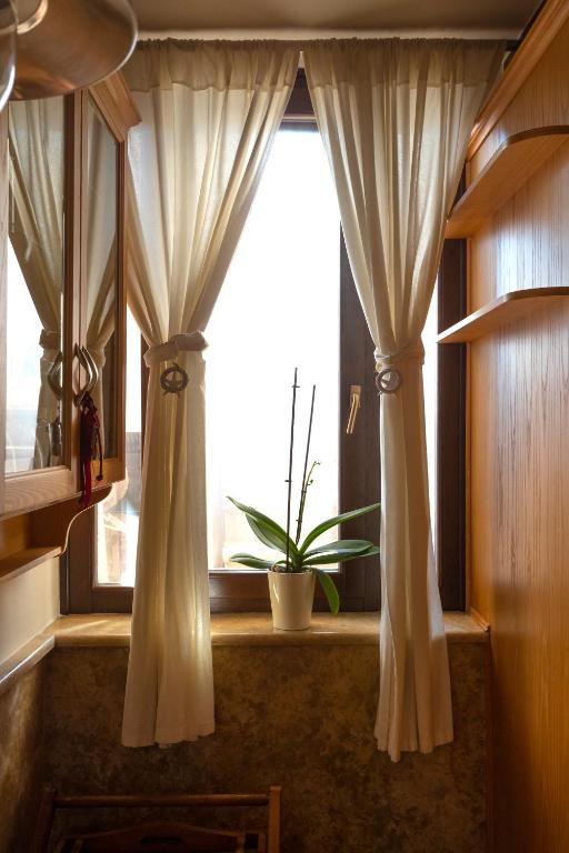 a window with curtains and a potted plant in a room at Flash House in Spetses