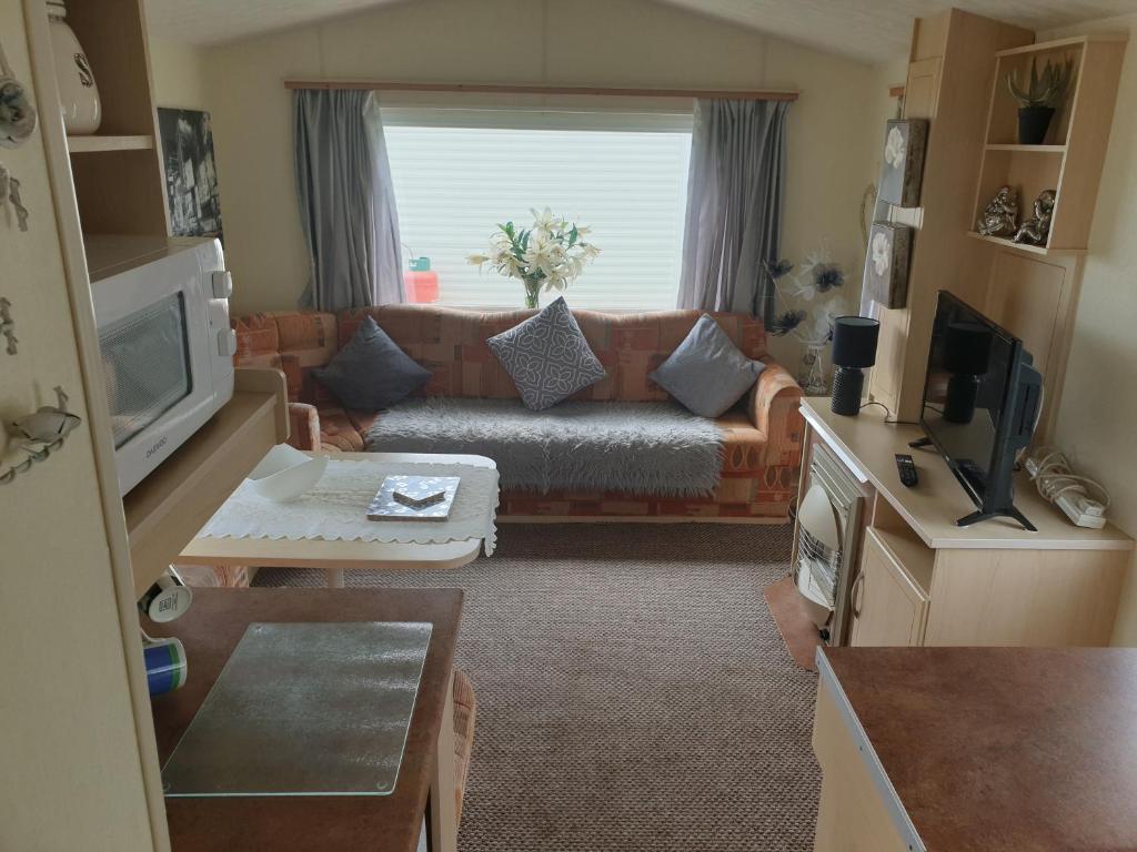 a living room with a couch and a large window at 4 BERTH CARAVAN SILVER BEACH INGOLDMELLS number 90 in Skegness