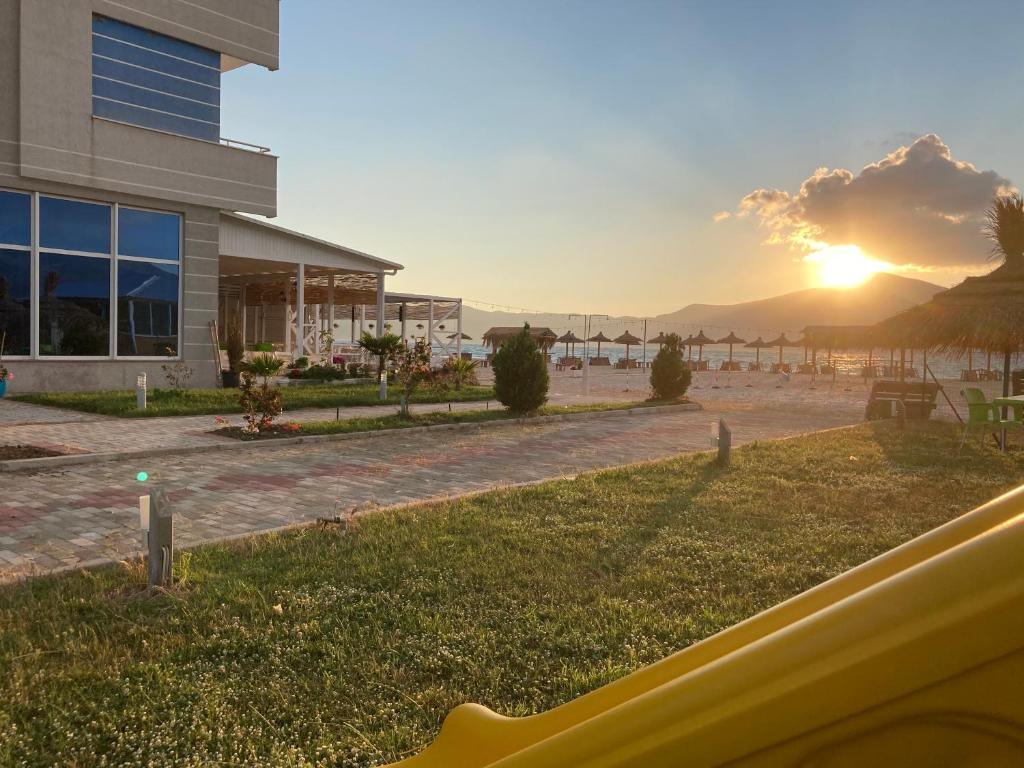 a view of a building and the beach at sunset at Blue Paradise Hotel in Orikum