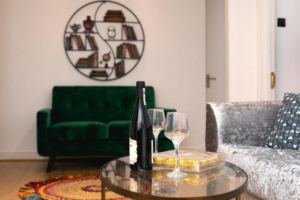 **Authentic & Spacious 5 Bed Apartment/Hyde Park** في لندن: غرفة معيشة مع أريكة خضراء وكؤوس للنبيذ