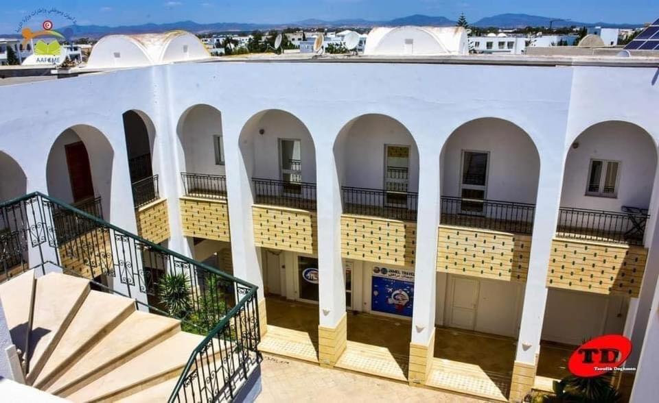 a large white building with arches and stairs at Résidence aladin in Hammamet Sud