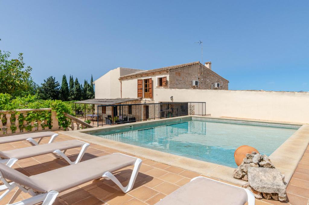 een zwembad met 2 ligstoelen en een huis bij YourHouse Son Morey, villa with private pool, family-friendly in Mora