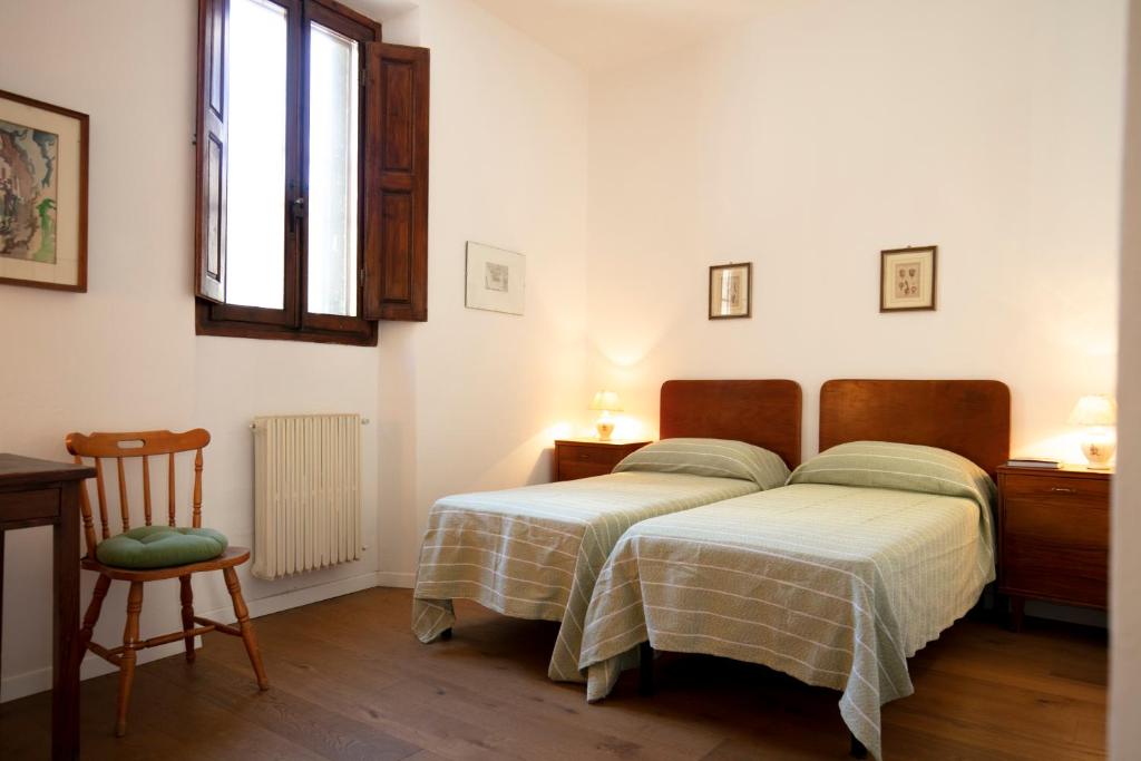sypialnia z 2 łóżkami, krzesłem i oknem w obiekcie Roommo Viuzzo delle Canne we Florencji