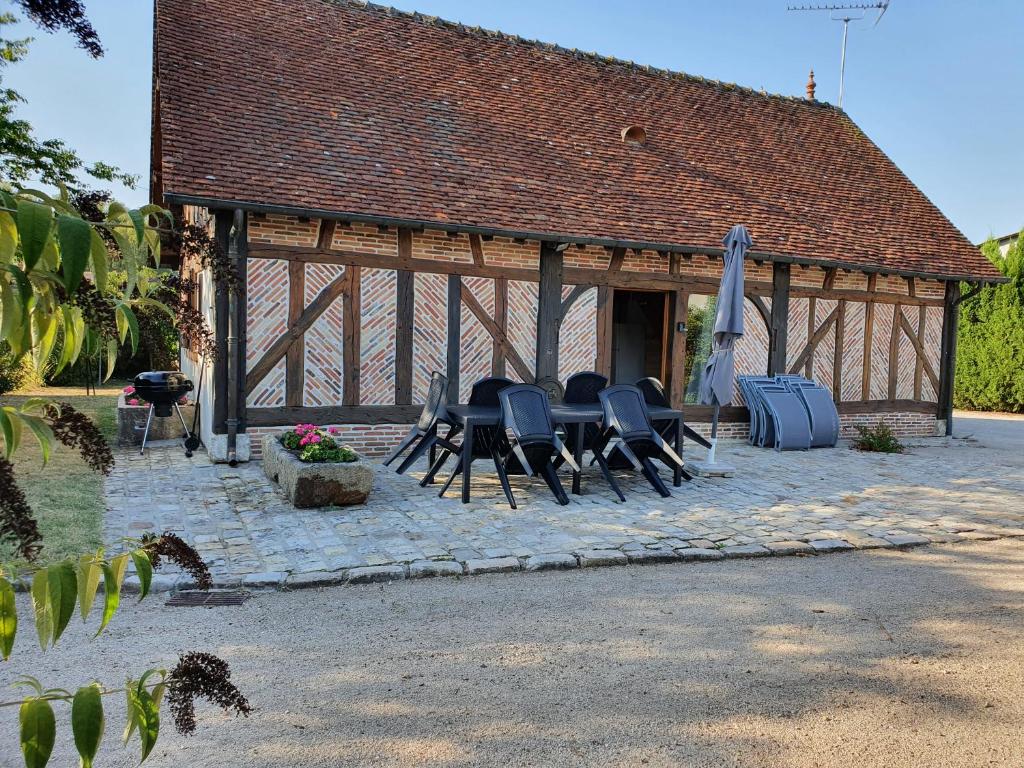 einer Gruppe von Stühlen und einem Regenschirm in einem Pavillon in der Unterkunft Gite les Bruyères in Salbris