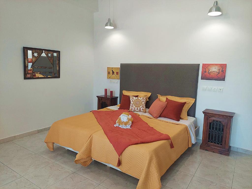 een slaapkamer met een groot bed met oranje dekens en kussens bij Apollonio Suites & Rooms Faliraki Rhodes in Faliraki
