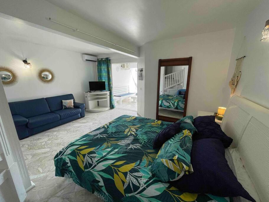 - une chambre avec un lit et un canapé bleu dans l'établissement Appart adorable proche de la baie orientale, Idolem résidence unité 2 - 57 Rue du Mont Vernon 1, à Cul de Sac