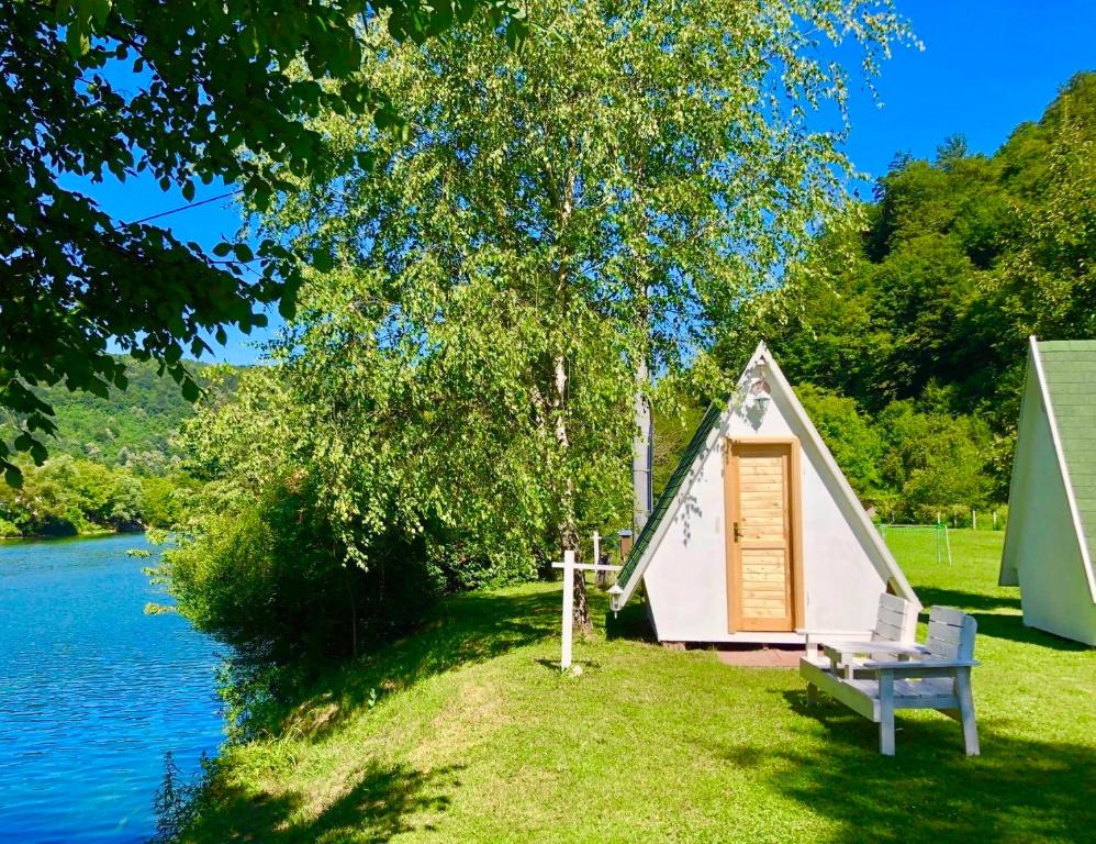 a small house with a bench next to a lake at Una Kamp in Bosanska Krupa
