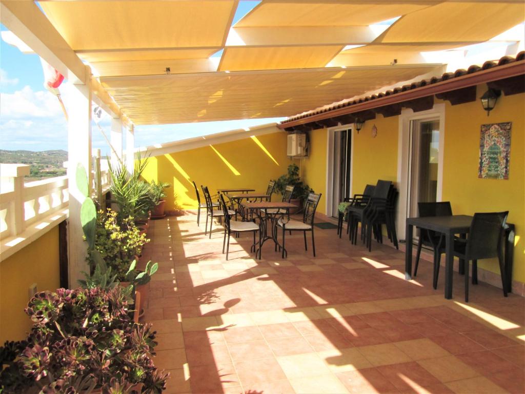 un patio con mesas y sillas en el balcón en B&B Le Terrazze Isola Di S. Antioco, en SantʼAntìoco