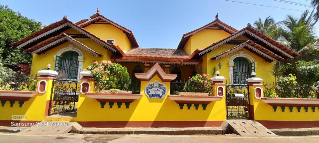 a yellow house with flowers in the windows at Villa Agastya in Betalbatim