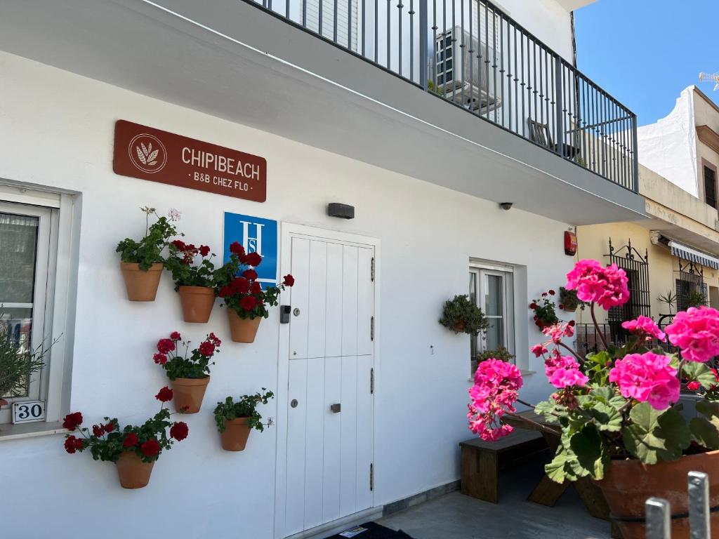 a white building with potted plants on the wall at Chipibeach, Hostal Boutique in Chipiona