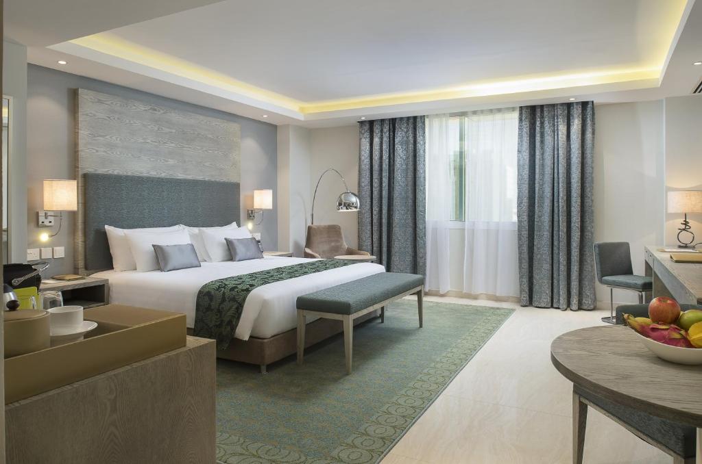 マスカットにあるCentara Muscat Hotel Omanのベッドとリビングルームが備わるホテルルームです。