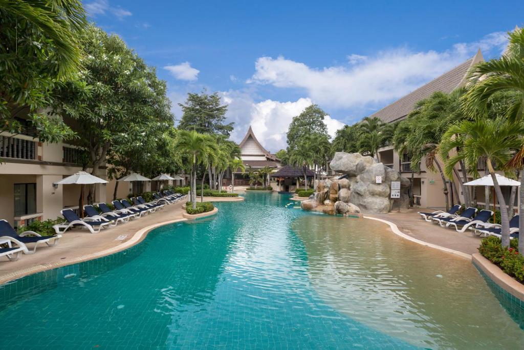 einen Pool in einem Resort mit Stühlen und einer Wasserrutsche in der Unterkunft Centara Kata Resort Phuket in Kata Beach