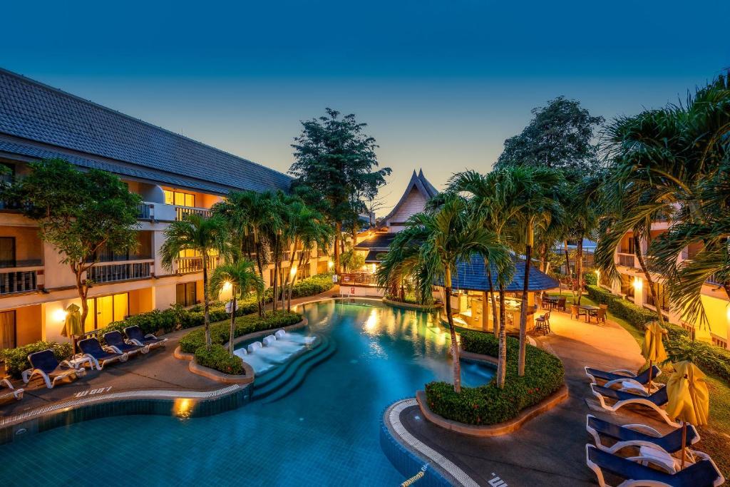 ein Bild eines Resortpools mit Stühlen und Palmen in der Unterkunft Centara Kata Resort Phuket in Kata Beach