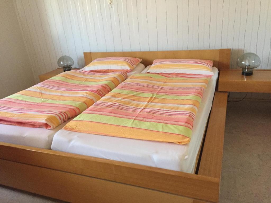 a bed with striped sheets on it next to a desk at Haus Rehm in Bad Säckingen