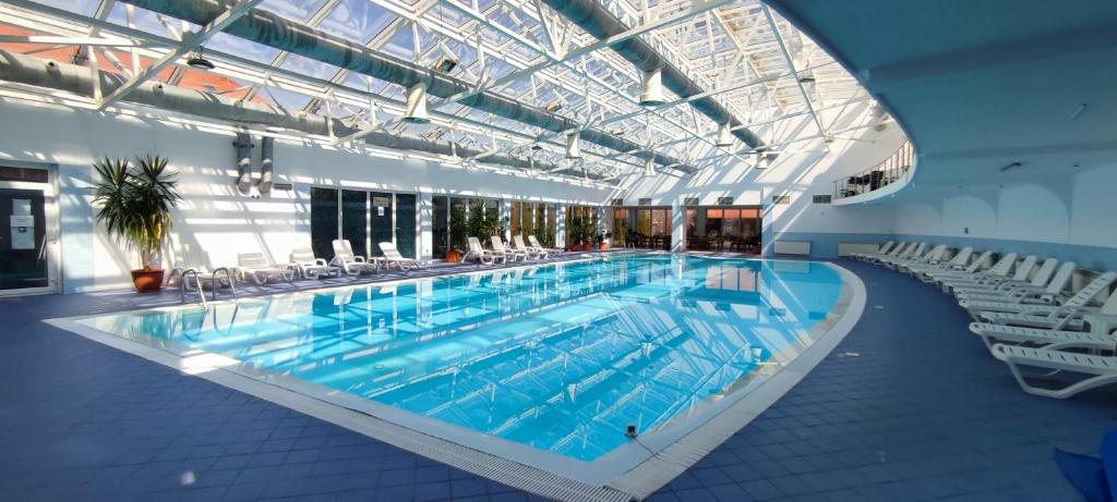 - une grande piscine avec des chaises dans un bâtiment dans l'établissement Mercure Medias Binderbubi Hotel And Spa, à Mediaş