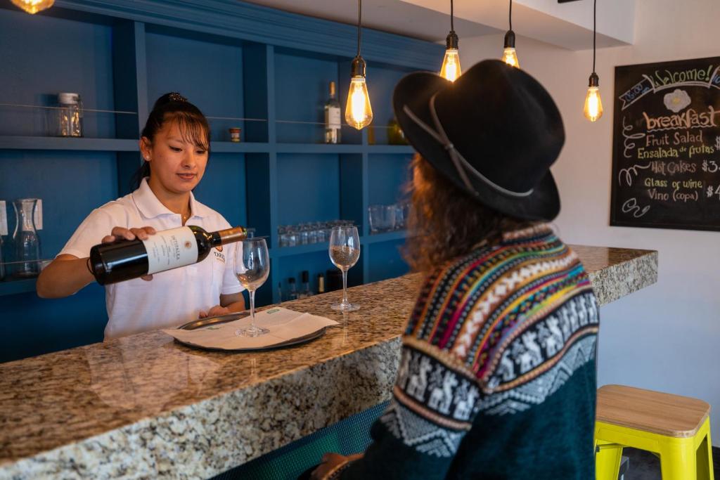 Una donna che versa un bicchiere di vino a un uomo di Tariq Boutique a Cuzco
