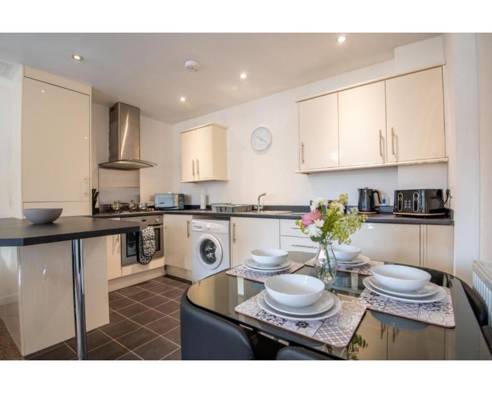 a kitchen with white cabinets and a table with dishes on it at No 2 Mansfield in Mansfield