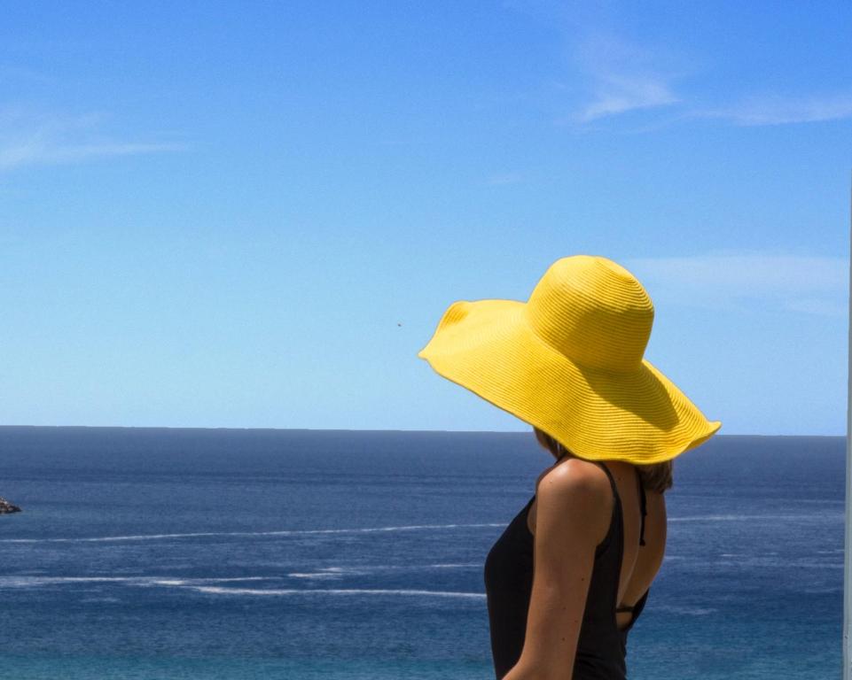 uma mulher com um chapéu amarelo a olhar para o oceano em ALK Hotel em Kamari