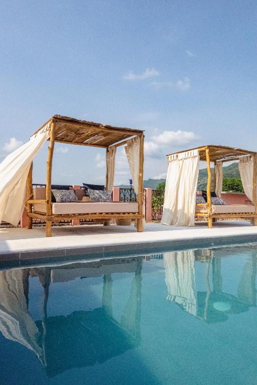 a pool with two beds next to the water at Casa De Amigos Hotel Boutique in Honda