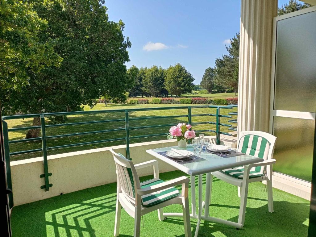 uma mesa e cadeiras numa varanda com vista em Appartement de standing dans le Golf International de La Baule em Saint-André-des-Eaux