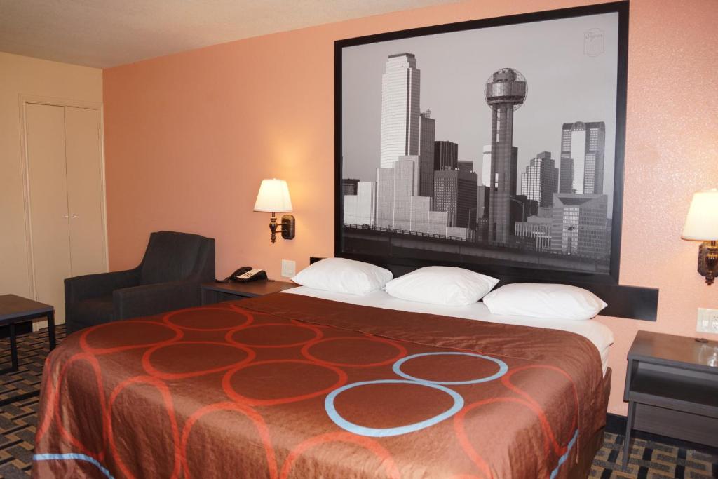 a hotel room with a bed with a large picture on the wall at Super 8 by Wyndham Farmers Branch/North Dallas in Farmers Branch