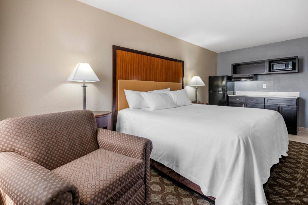una camera d'albergo con letto e sedia di Suburban Studios Lafayette a Lafayette