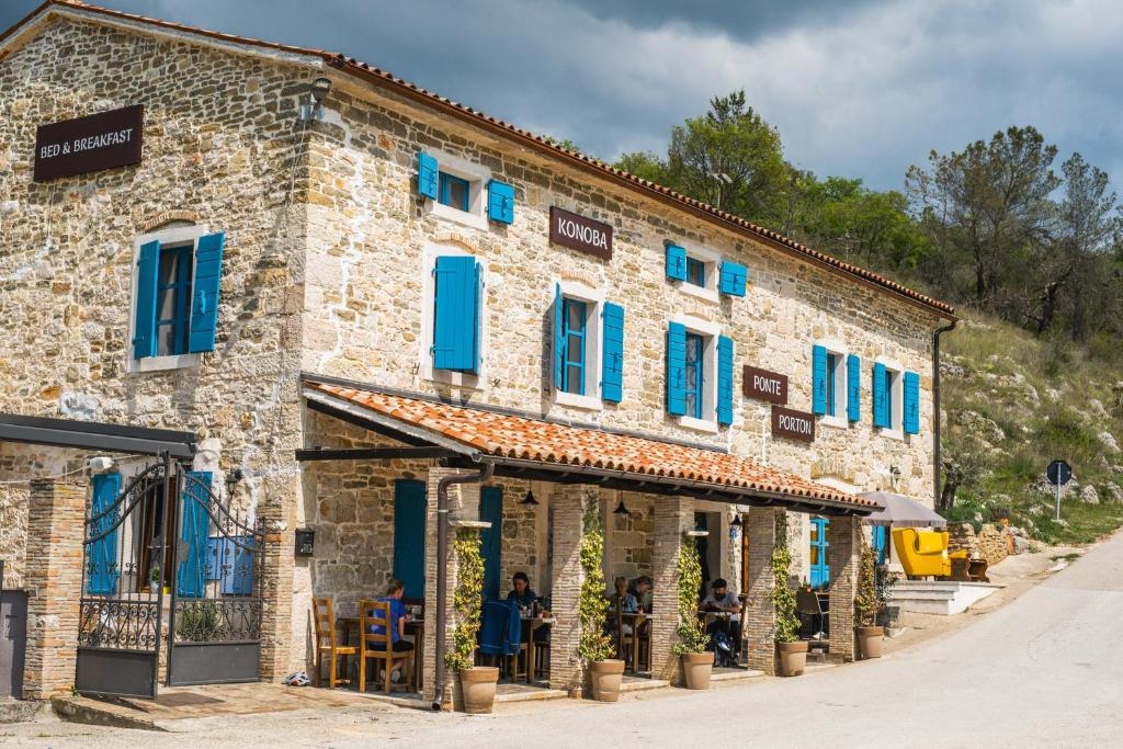 a building with blue shutters and people sitting outside at Ponte Porton Dining & lodging in Grožnjan