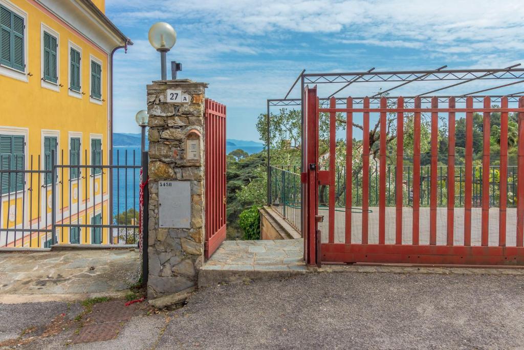 a red gate with a stone pillar next to a building at La casa dei Gabbiani by Portofino Homes in Santa Margherita Ligure