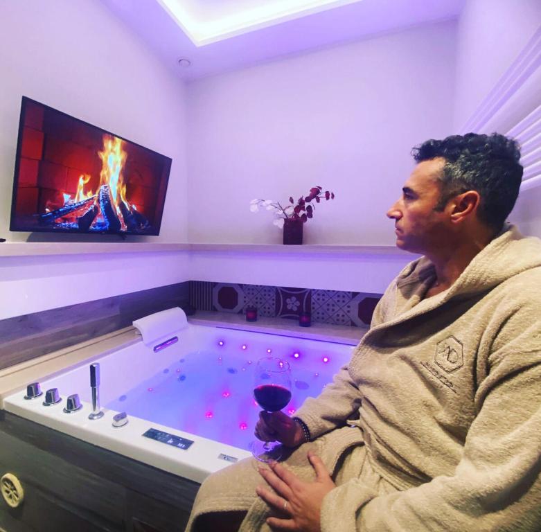 a man sitting in a hot tub with a wine glass at Bed & breakfast Mad Suite Bernalda in Bernalda