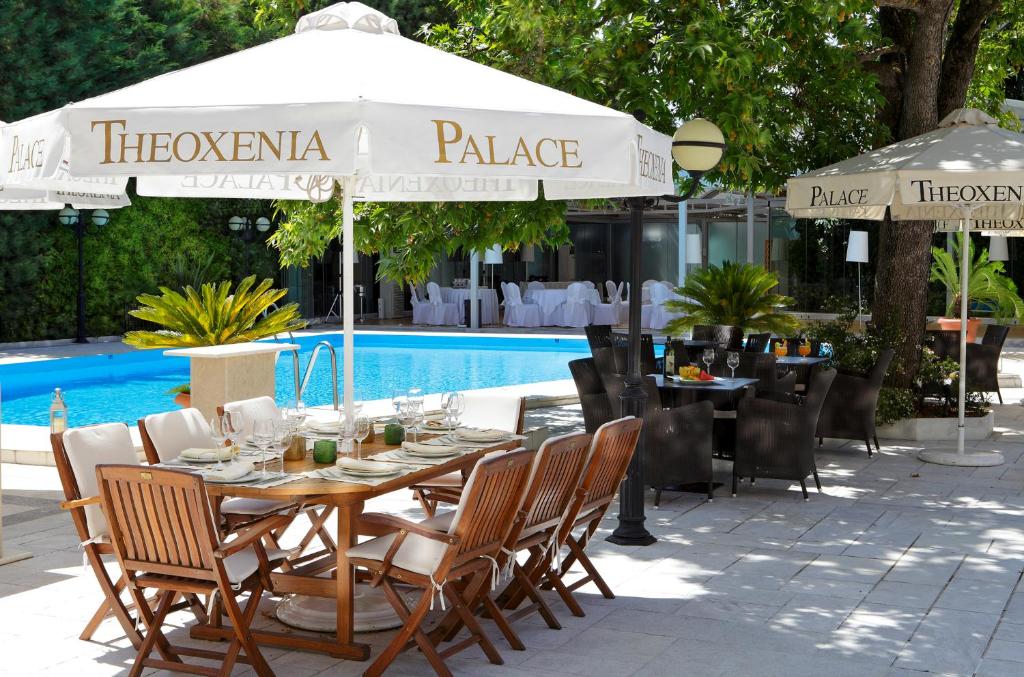 een tafel met stoelen en een parasol naast een zwembad bij Theoxenia Residence in Athene