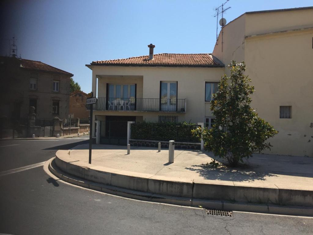 a building with a tree in front of a street at Appartement proche du canal du midi in Colombiers