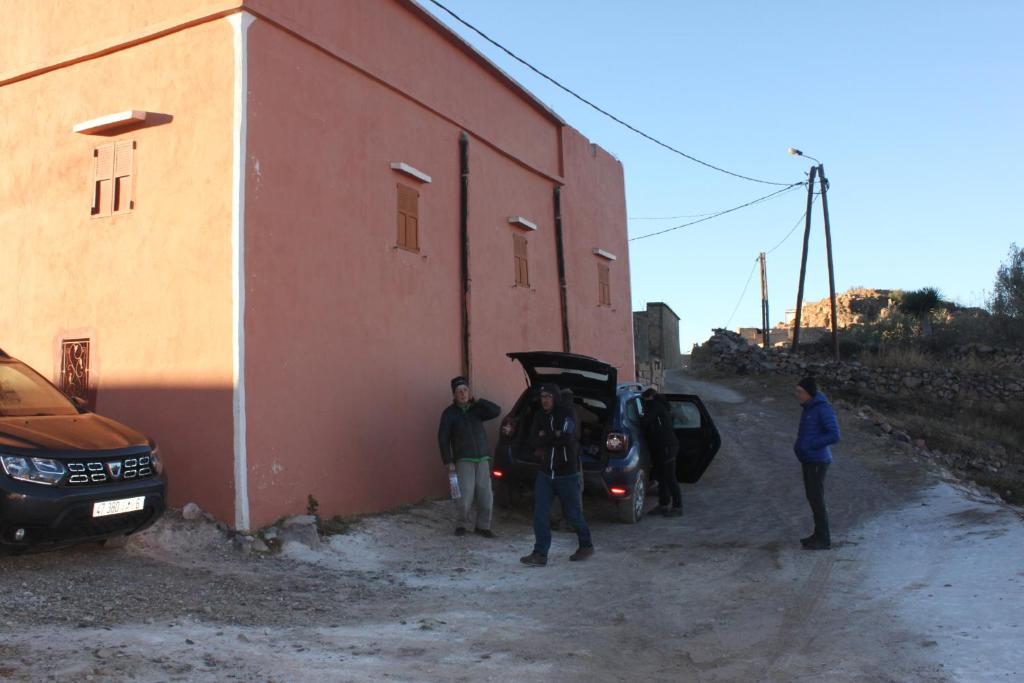 eine Gruppe von Menschen, die neben einem Gebäude mit einem Auto stehen in der Unterkunft Ajgal imzi in Tiznit