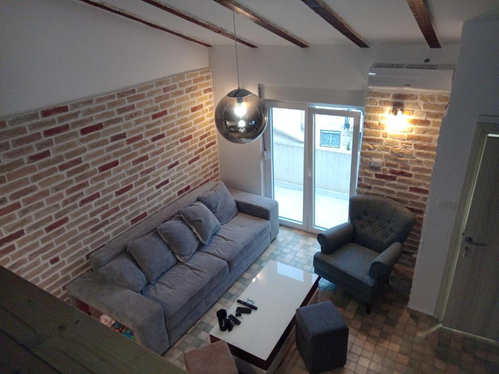 sala de estar con sofá y pared de ladrillo en Budva stan Natasa, en Budva