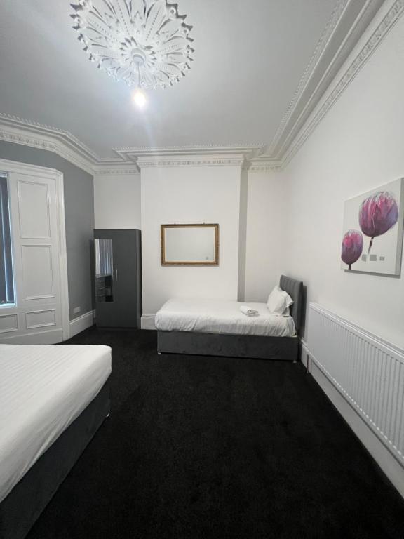 Dieses weiße Zimmer verfügt über 2 Betten und einen Kronleuchter. in der Unterkunft New modern Private House central location in Newcastle upon Tyne