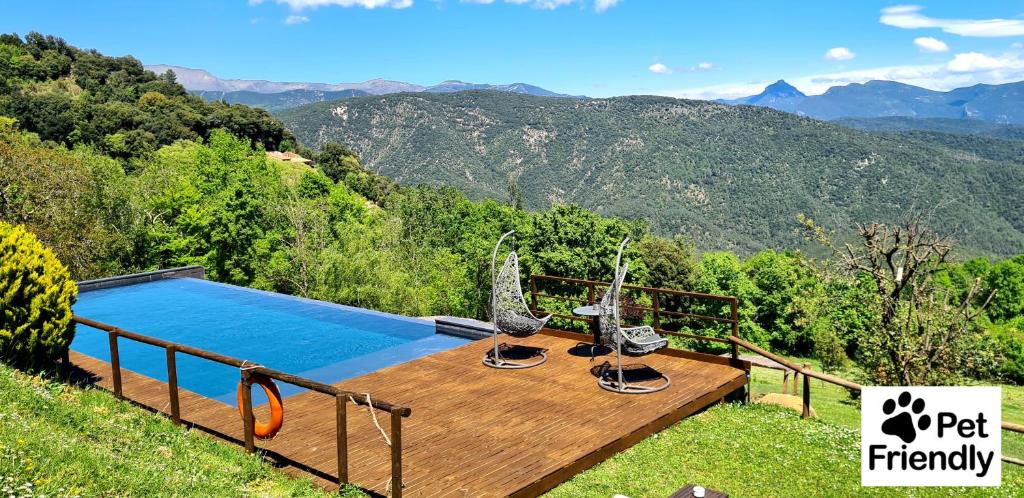 una piscina en una terraza de madera con vistas a las montañas en Hotel Rural & Spa Mas Prat, en Vall de Bianya