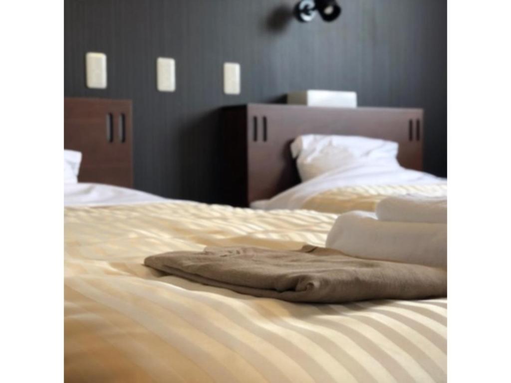uma cama com lençóis brancos e almofadas em HOTEL COONEL INN - Vacation STAY 33523v em Susono