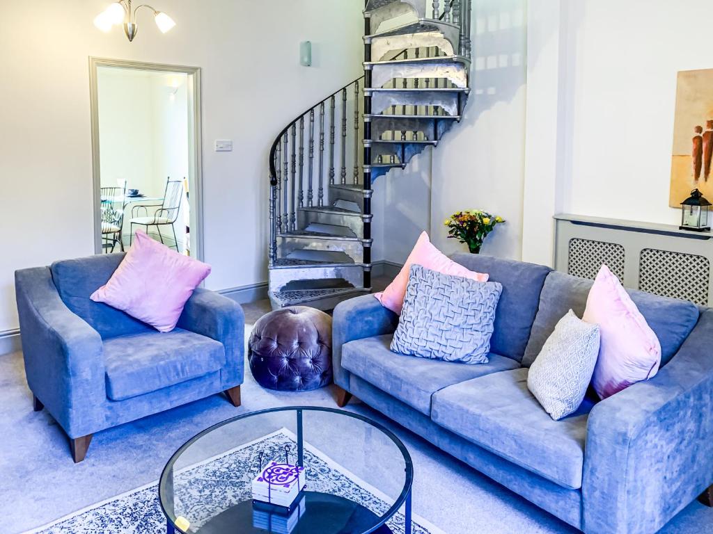 a living room with two blue couches and a glass table at Stay In The Heart Of 'Bishy Road' At The Vines With Free Parking - York Holiday Home in York