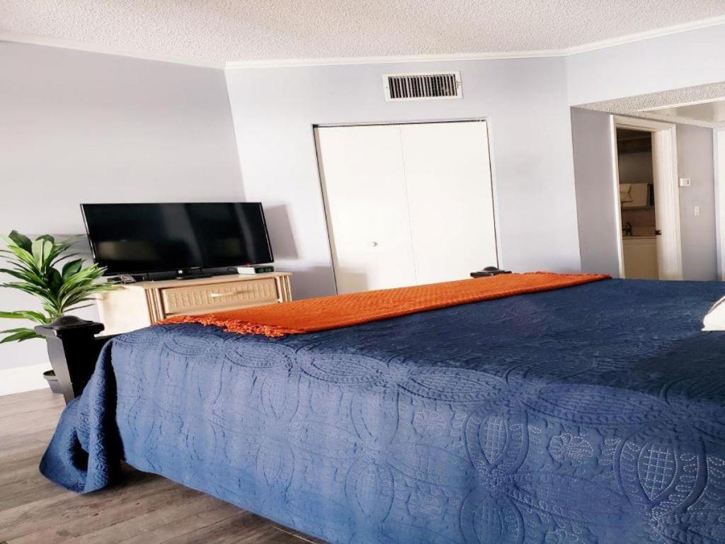 een slaapkamer met een blauw bed en een flatscreen-tv bij Inn at Camachee Harbor View 12 in St. Augustine