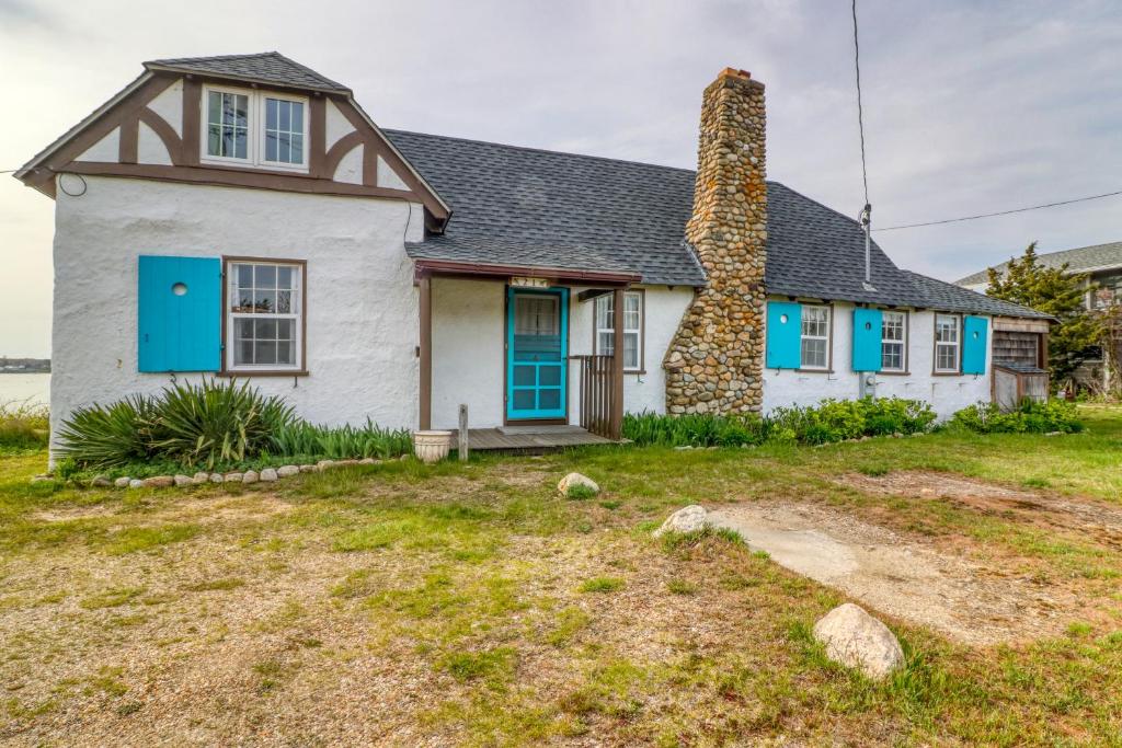 Casa blanca con ventanas azules y chimenea en Wild Oak Oasis, en Oak Bluffs