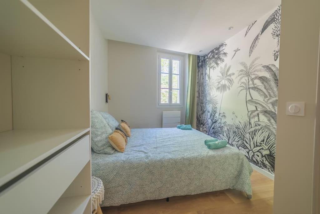 Habitación pequeña con cama y mural en la pared en Le Palm Appartement élégant & Design En Bord Rivière en Collobrières