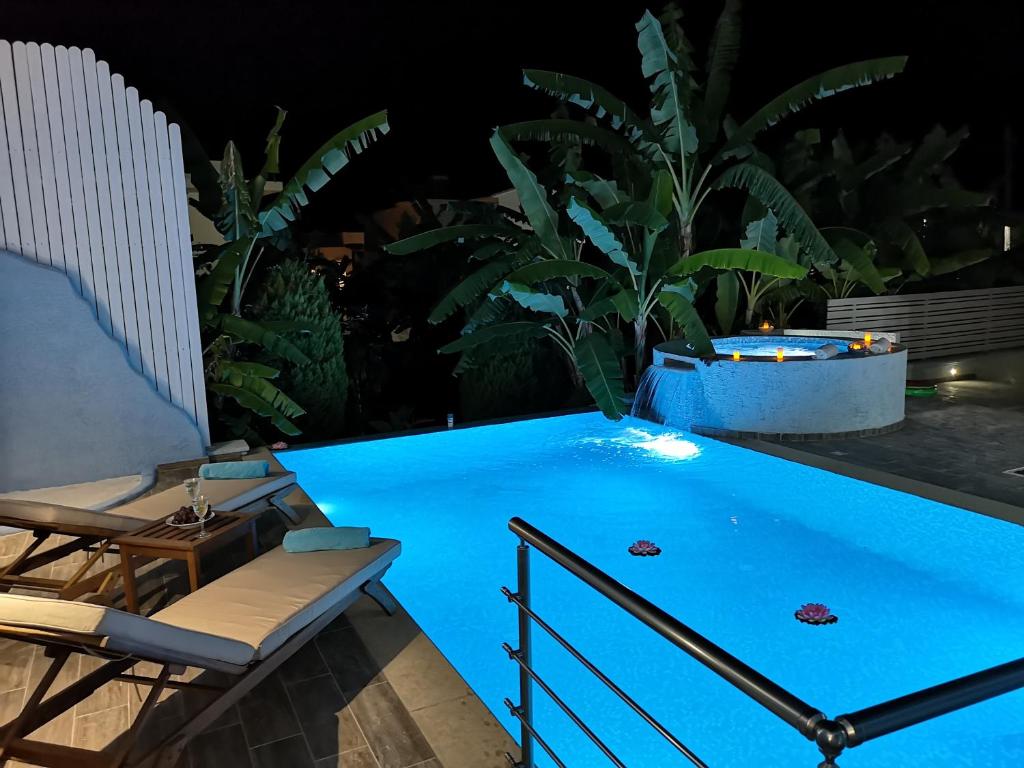 a swimming pool at night with two chairs and a table at Valantas Garden Suite in Lartos