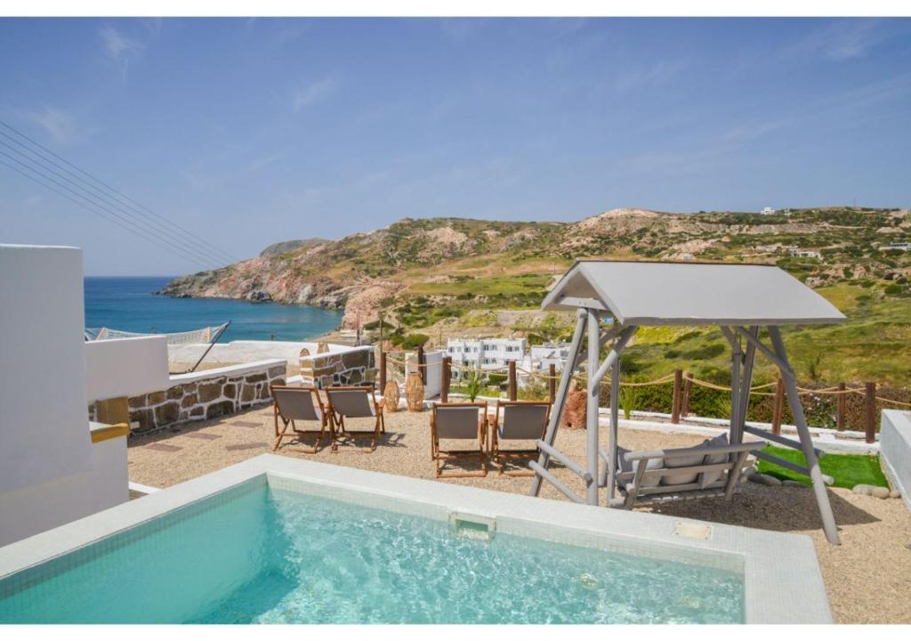 una piscina con sillas, un cenador y el océano en Avgerinos Deluxe Rooms, en Paliochori