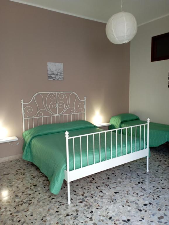 a bedroom with a white bed with a green blanket at Apartment Casa Francesca in Syracuse