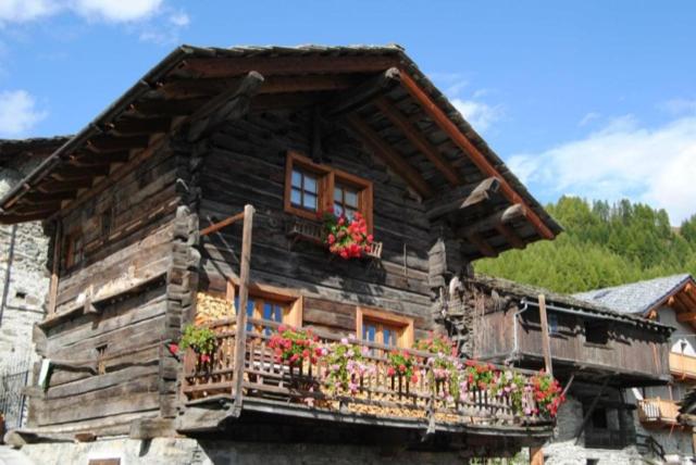 une maison en bois avec des fleurs sur un balcon dans l'établissement Piccolo e accogliente rascard CIR 0060, à Champoluc