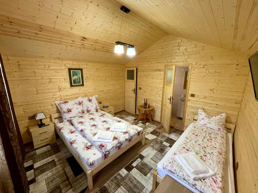 1 Schlafzimmer mit 2 Betten in einer Holzhütte in der Unterkunft Căsuțele din Retezat in Nucşoara