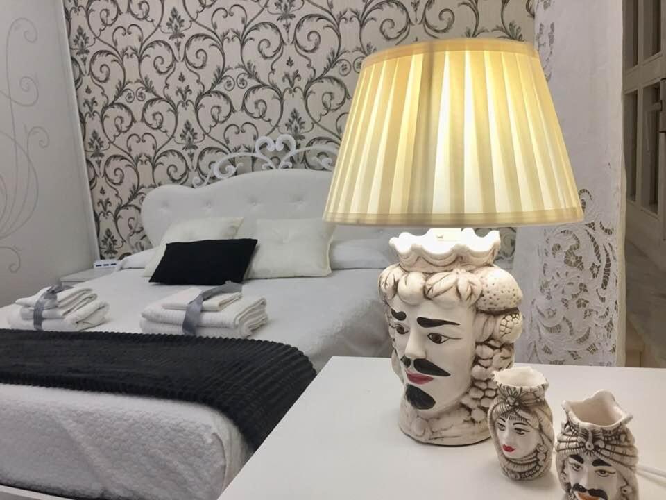 a bedroom with a bed and a lamp on a table at Il giardino in Canicattì