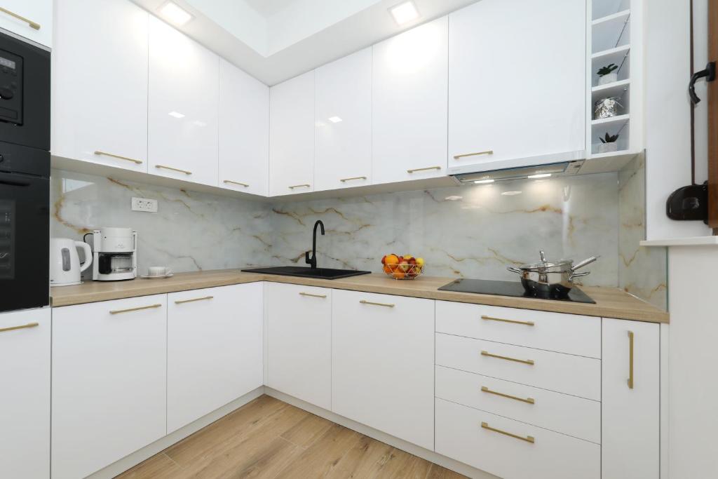 a white kitchen with white cabinets and a sink at Apartment and room Mare in Zadar